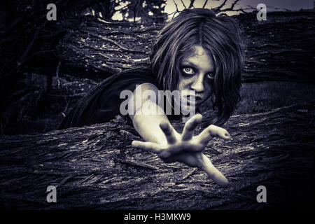 Haunted abgebildet von Kind Crawling in dunklen Friedhof unter alten Bäumen Stockfoto