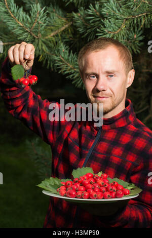 junger Mann mit der Frucht des Weißdorn Stockfoto