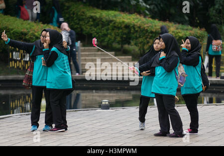 Eine Gruppe von muslimischen Mädchen tragen Hijab unter Selfies auf dem Handy in der Nähe von den Petronas Twin Towers, Kuala Lumpur, Malaysia Stockfoto