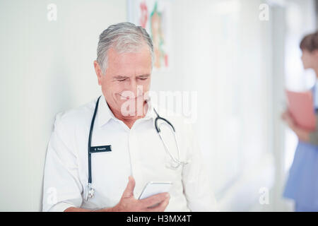 Männliche Oberärztin lesen Smartphone Nachricht im Krankenhaus Stockfoto