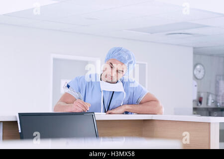 Männlichen Arzt medizinische Notizenschreiben an Krankenschwestern Station im Krankenhaus Stockfoto