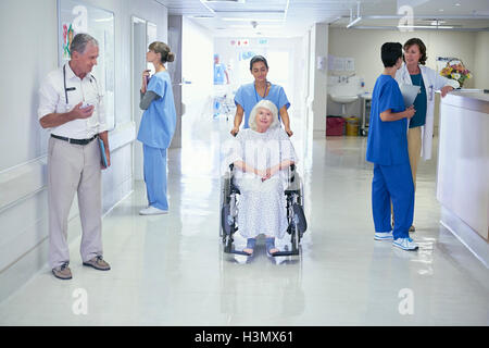 Krankenschwester drängen ältere Patientin im Rollstuhl auf Krankenstation Stockfoto