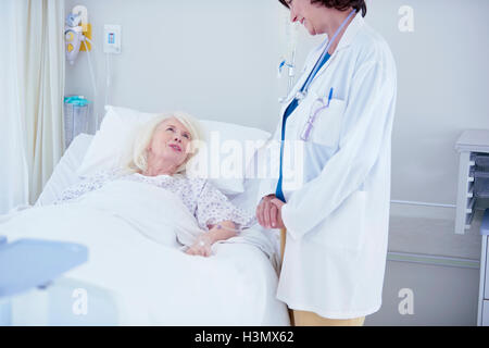 Ärztin im Gespräch mit älteren Patientin im Krankenhausbett Stockfoto
