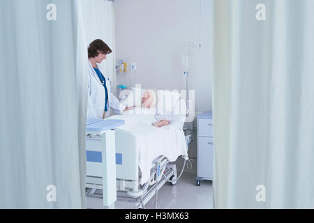 Ärztin im Gespräch mit älteren Patientin im Krankenhausbett Stockfoto