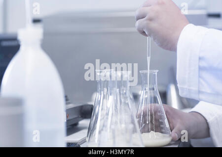 Wissenschaftler Pipettieren Probe in Becherglas im Labor Stockfoto