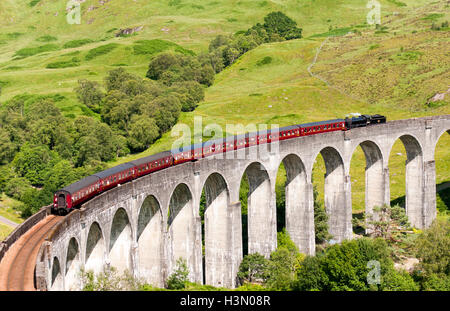 Dampfzug auf Glenfinnan Viadukt, gewölbte Eisenbahnbrücke auf West Highland Line in Schottland, Großbritannien Stockfoto