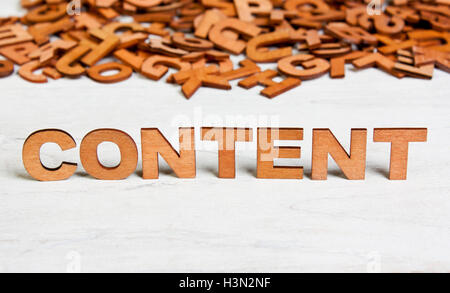 Wort-Content mit Holzbuchstaben auf einem Hintergrund von anderen verschwommenen Buchstaben gemacht Stockfoto