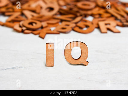 Wort-IQ (Intelligenzquotient) mit Holzbuchstaben auf einem Hintergrund von anderen verschwommenen Buchstaben gemacht Stockfoto