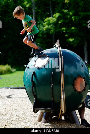 Ein kleiner Junge (4 Jahre alt) einen Sprung von einer Spielplatz-Installation. Stockfoto