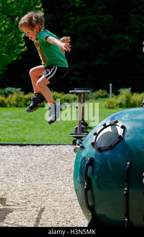 Ein kleiner Junge (4 Jahre alt) einen Sprung von einer Spielplatz-Installation. Stockfoto