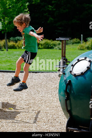 Ein kleiner Junge (4 Jahre alt) einen Sprung von einer Spielplatz-Installation. Stockfoto