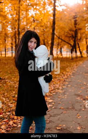 Junge Mutter mit ihrem Baby auf der Seite im Herbst park Stockfoto