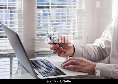Junger Erwachsener mit Handy und Laptop zu Hause Stockfoto