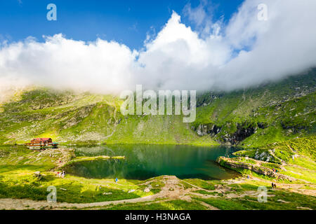 Balea See und Chalet im Fagaras-Gebirge, Rumänien. Nicht identifizierbare Touristen genießen die Landschaft. Stockfoto