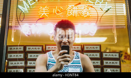 Mann mit Handy vor Fenster des chinesischen Geschäft Stockfoto