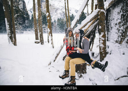 Frau sitzt auf mans Runde im tief verschneiten Landschaft Stockfoto