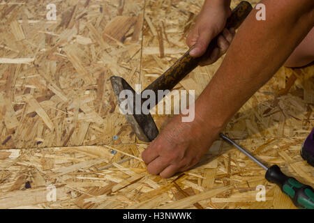 Ein Nagel gehämmert in Holz, Men at Work. Stockfoto