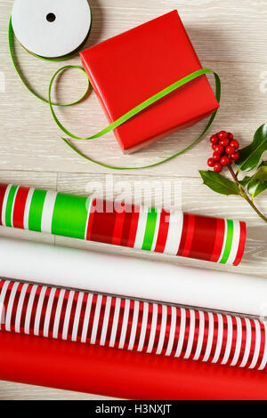 Rote und grüne Weihnachten Geschenkpapier Lieferungen Geschenkpapier, Geschenk-Box, präsentieren, Bänder und natürlichen botanischen Stechpalme Beeren Stockfoto