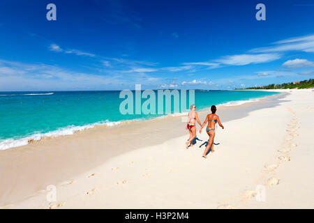 Zwei junge Frauen zu Fuß den Sandstrand in Nassau, Paradise Island. Stockfoto