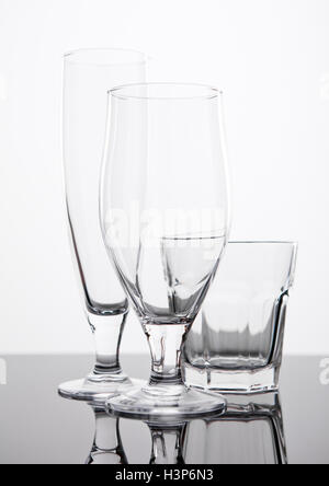 Bier und Whisky Gläser am schwarzen Brett auf weißem Hintergrund reflektiert Stockfoto