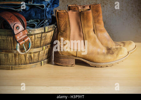 Leder-Schuhe und Kleidung im Korb auf dem Holz. Stockfoto