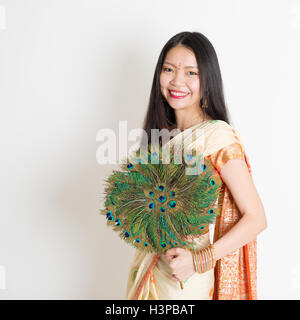 Porträt des jungen Mischlinge indische chinesische Frauen in traditionellen Sari Kleid hält Pfau Federn Fan und Blick in die Kamera Stockfoto