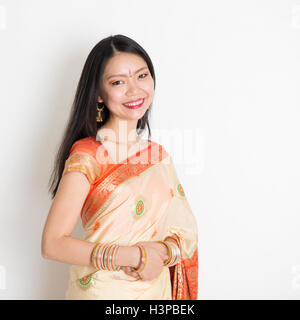 Porträt von Mischlinge indische Chinesin mit traditionellen Sari Kleid lächelnd, stehend auf einfarbigen Hintergrund. Stockfoto