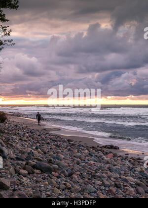 Surfer Spaziergänge am Strand bei Sonnenuntergang Stockfoto