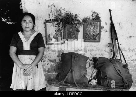 CHALATENANGO, EL SALVADOR, FEB 1984: - im Rahmen der FPL-Guerilla Zonen des Steuerelements.  Ein Ladenbesitzer vor ihrem Haus.  Die Pistole und Taschen gehören Volksmiliz Mitgliedern auf der Durchreise. Stockfoto