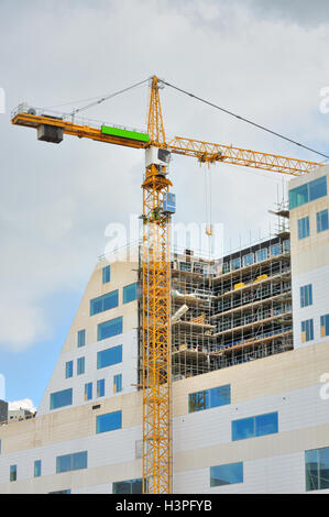 Arbeitet der Kran auf einem modernen Bürogebäude im Bau Stockfoto