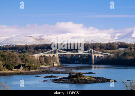 Menai Hängebrücke über Menaistraße mit Schnee auf Carneddau Berge von Snowdonia jenseits im Winter. Menai Bridge ANGLESEY Wales England Großbritannien Stockfoto