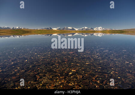 Highland klaren See mit sauberen, transparenten Kristallwasser und Steinen am Boden auf einem Hintergrund von Schnee Eis bedeckt Hochgebirge Stockfoto