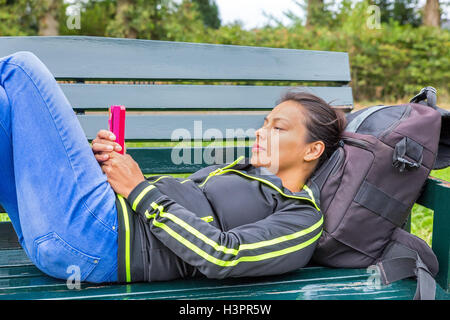 Europäerin Handy auf Bank liegend in Betrieb Stockfoto