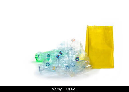 Haufen von Kunststoff-Flaschen liegt auf dem weißen Hintergrund. Die gelben Leerbeutel steht neben ihnen. Stockfoto