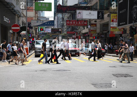 Menschen überqueren einer viel befahrenen Straße im Zentrum von Hongkong Stockfoto