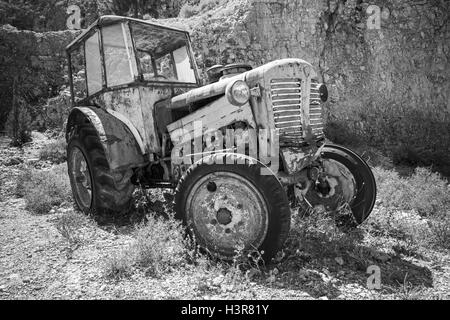 Alte verlassene verrosteten Traktor steht auf Trockenrasen. Schwarz / weiß Foto Stockfoto