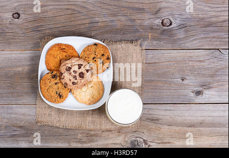 Draufsicht auf eine Vielzahl von frisch gebackenen Plätzchen auf einer Serviette mit einem Glas Milch. Stockfoto