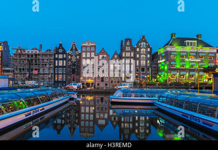 AMSTERDAM, Niederlande - 3. April 2008: Ausflugsboote und tanzenden Häuser auf dem Damrak Kanal von Nachtlicht beleuchtet Stockfoto