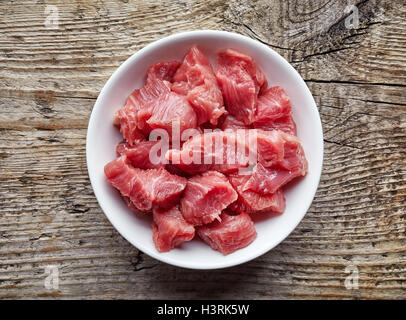 Weiße Schale mit rohe gewürfelte Rindfleisch auf Holztisch, Ansicht von oben Stockfoto