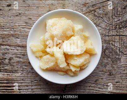 Stücke von Parmesan-Käse in weiße Schüssel auf Holztisch, Ansicht von oben Stockfoto