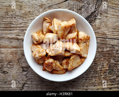 Weiße Schale mit gegrilltem Hühnerfleisch auf Holztisch, Ansicht von oben Stockfoto