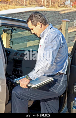 Ein Geschäftsmann setzen seine Computer im Auto immer bereit zu gehen zu arbeiten. Stockfoto