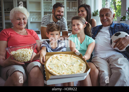 Mehr-Generationen-Familie sitzt mit Popcorn und Pizza beim Fußballspiel ansehen Stockfoto