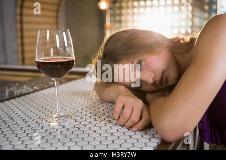 Frau liegt auf Bartheke mit Weinglas auf Tisch Stockfoto