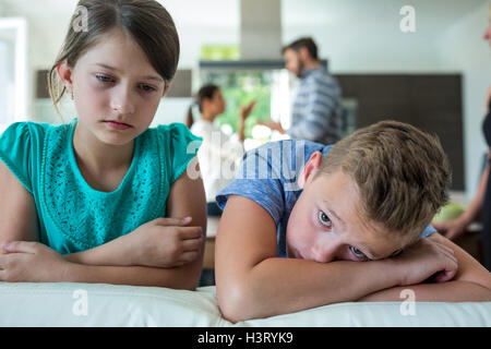 Traurige Kinder stützte sich auf Sofa, während Eltern streiten im Hintergrund Stockfoto