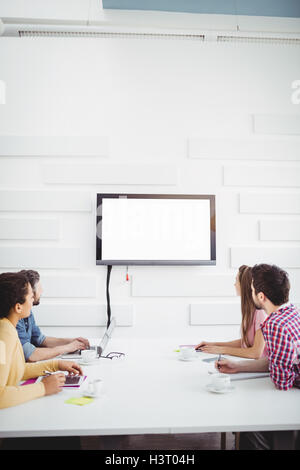 Geschäftsleute, die gerade im Fernsehen an Wand Kreativbüro Stockfoto
