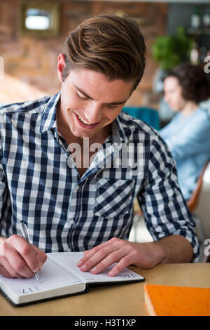 Menschen, die Schreiben von Notizen im Tagebuch in Coffee-shop Stockfoto