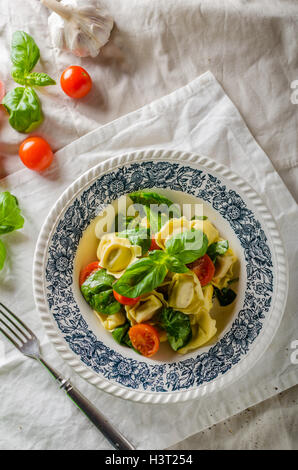 Tortellini gefüllt mit Fleisch mit gerösteten Tomaten und Basilikum, Olivenöl Stockfoto