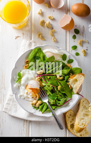 Lamm-Salat mit gebratenem Ei, frisch gepresster Orangensaft und gerösteten Nüssen und Baguette Stockfoto