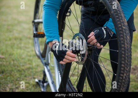 Männliche Mountainbiker Vorderrad seines Fahrrades prüfen Stockfoto